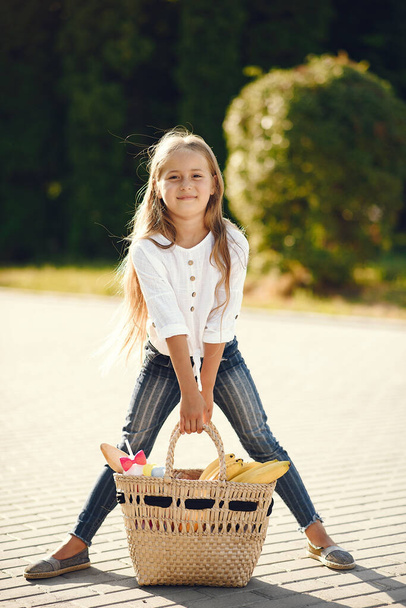 Little girl in a park standing with brown basket - Fotoğraf, Görsel