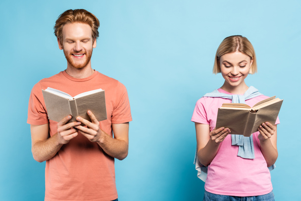 young redhead and blonde students reading books on blue - Photo, image