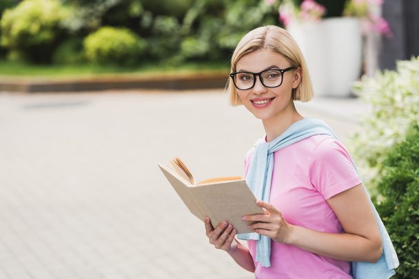 young blonde student in glasses holding book outside  - Photo, Image