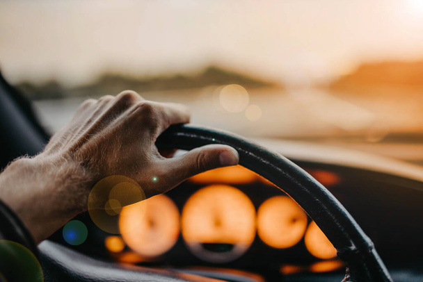 driving a car, hand on the steering wheel at sunset. - Photo, Image