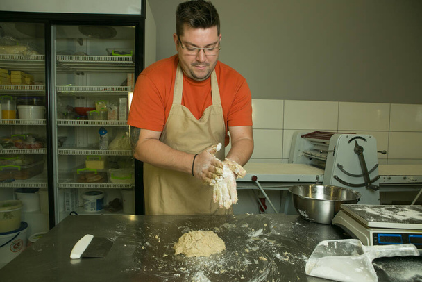 Η διαδικασία της παραγωγής ψωμιού. Ο σεφ ζυμώνει τη ζύμη με το χέρι. - Φωτογραφία, εικόνα