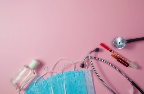 Covid-19, coronavirus treatment. Pills, stethoscope and medical masks on pink background. - Fotó, kép