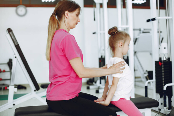 Mother with little daughter are engaged in gymnastics in the gym - Foto, Imagen