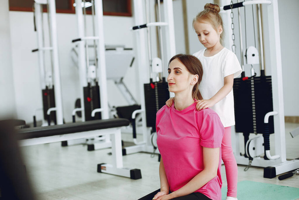 Mother with little daughter are engaged in gymnastics in the gym - Foto, afbeelding