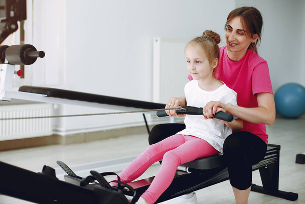 Mother with little daughter are engaged in gymnastics in the gym - Fotó, kép