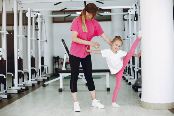 Mother with little daughter are engaged in gymnastics in the gym - Foto, imagen