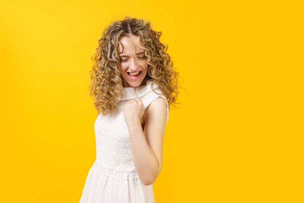 Young woman gestures yes with hand. Female portrait. Isolated on yellow background - Foto, Imagen