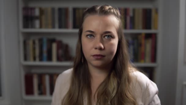 Woman psychologist nods and agrees portrait against background of books - Footage, Video