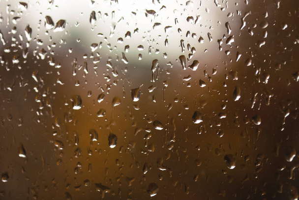 Close-up oranje regendruppels op het glas, regenseizoen in de herfst. - Foto, afbeelding