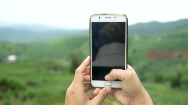 Toerist genieten van de natuur en neem foto 's met smartphone op de bergachtige achtergrond. - Video