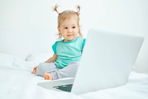Happy toddler sits and looks at the laptop - Foto, afbeelding