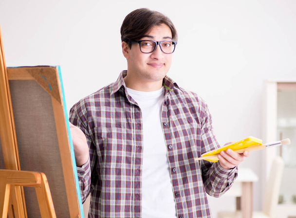 Jonge mannelijke kunstenaar tekening foto 's in heldere studio - Foto, afbeelding