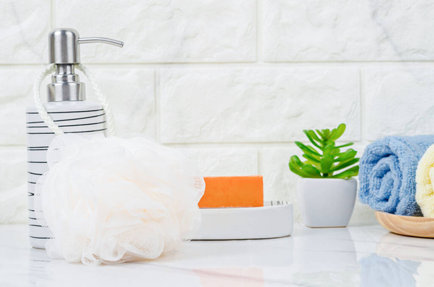 Shower sponge and shampoo pump bottle with herbal soap inside a bright bathroom background. - Фото, зображення