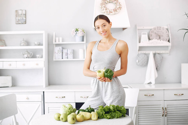 Beautiful and sporty girl in a kitchen with a vegetables - Valokuva, kuva