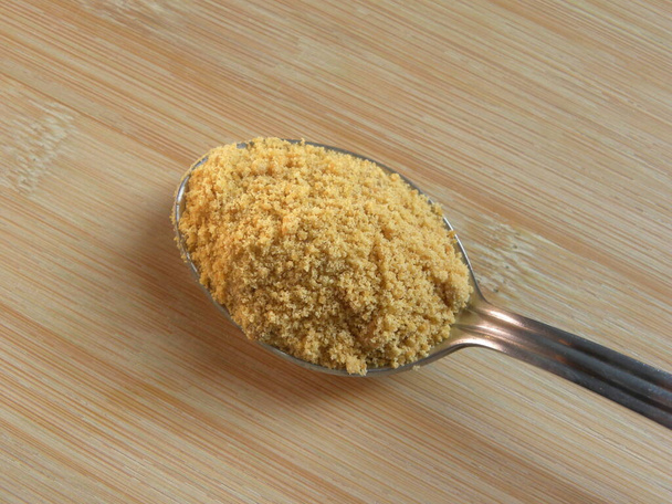 Gelbe Farbe Zuckerrohr-Jaggery-Pulver auf Edelstahllöffel - Foto, Bild