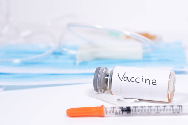 Macro photography of a syringe ready to put a vaccine and medical vessel with white label - Foto, immagini