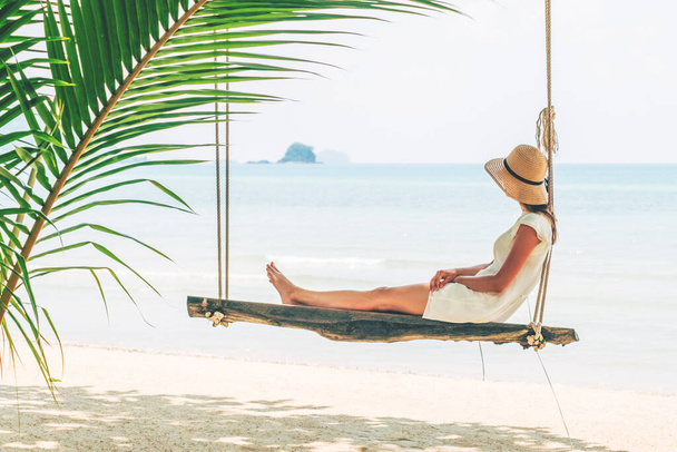 Young woman sitting on a beach swing. Happy female traveller. Vacation concept - Foto, Bild