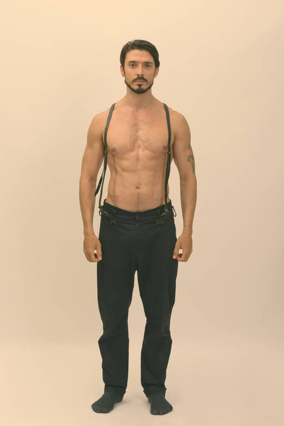 Студийный снимок молодого красивого мускулистого бородатого мужчины без рубашки на белом фоне - Фото, изображение