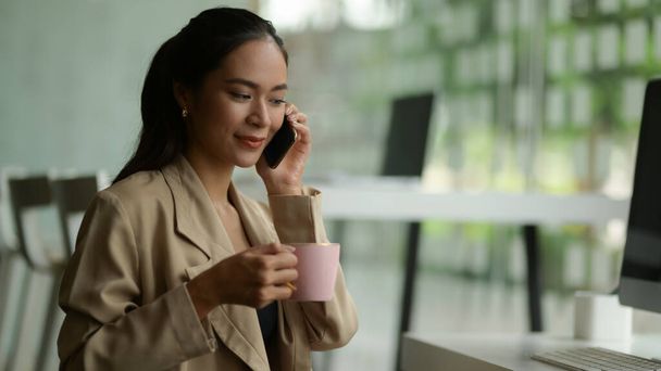 Zamknij widok kobiety przedsiębiorcy rozmawiając przez telefon podczas przerwy na kawę w biurze - Zdjęcie, obraz
