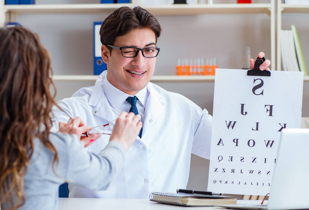 Lekarz optyk z wykresem literowym przeprowadzający badanie wzroku - Zdjęcie, obraz
