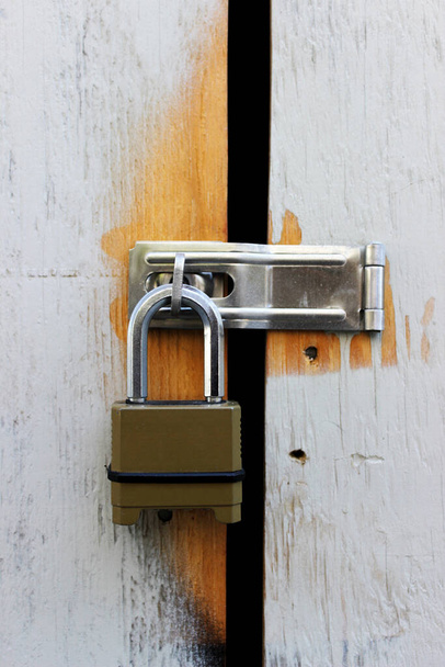 A metal padlock on the white wooden door. Padlock on the door. - Фото, зображення
