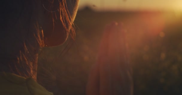 Makro szczegółowy portret dziewczynki modlącej się na zewnątrz oświecony złotym światłem zachodu słońca. Widok z tyłu młodej kobiety trzymającej się za ręce w Namaste znak spowolnienia ruchu. Religia stres przezwyciężyć koncepcję - Materiał filmowy, wideo