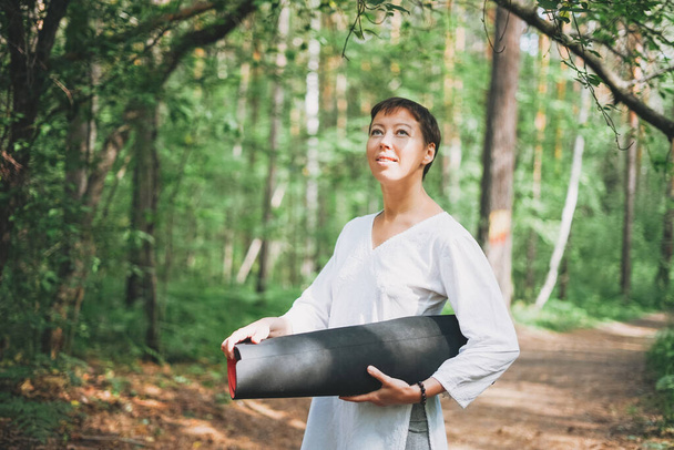 Jonge lachende vrouw beoefent buiten yoga in het bos. Lichamelijke en geestelijke gezondheid - Foto, afbeelding