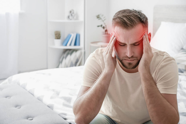 Młody człowiek cierpiący na ból głowy w domu - Zdjęcie, obraz