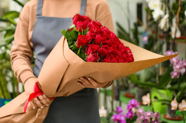 Myyjä kukkakimppu kauniita punaisia ruusuja kaupassa - Valokuva, kuva