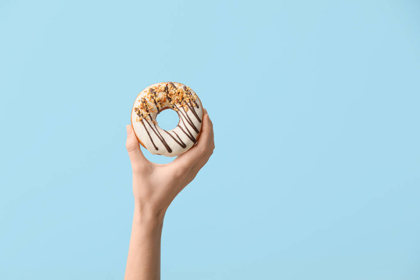 Hand with tasty donut on color background - Photo, image