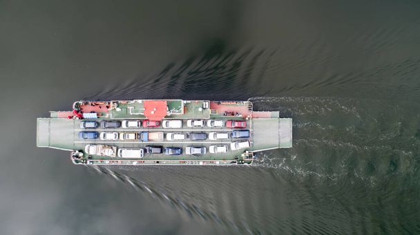 vista de arriba hacia abajo de la navegación en ferry. Ferryboat transfiriendo coches. Ferry transfiere coches y pasajeros al otro lado - Foto, imagen