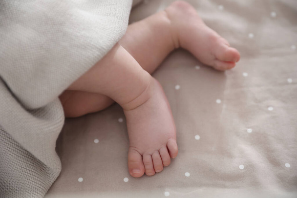 Cute little baby lying in bed, closeup of feet. Bedtime - Photo, Image