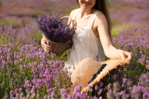 Mujer joven con sombrero de paja en el campo de lavanda en el día de verano, primer plano - Foto, Imagen