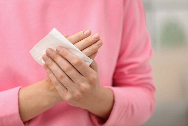 Woman cleaning hands with paper tissue on blurred background, closeup - Foto, Imagem