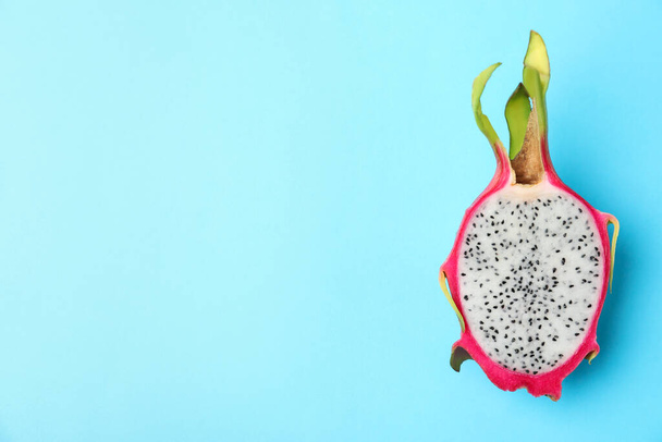 Half of delicious ripe dragon fruit (pitahaya) on light blue background, top view. Space for text - Foto, Imagen