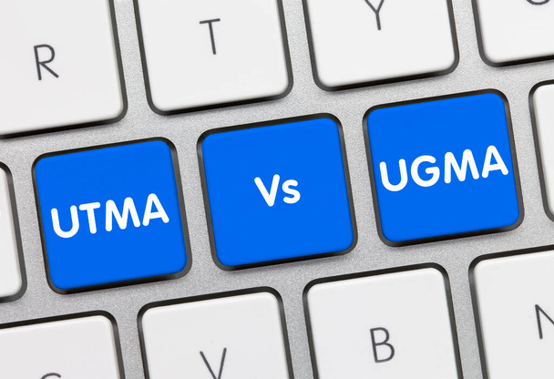 UTMA Vs UGMA Γραμμένο σε μπλε κλειδί από μεταλλικό πληκτρολόγιο. Πληκτρολόγιο πληκτρολογίου. - Φωτογραφία, εικόνα
