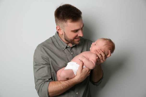 Father with his newborn son on light grey background - Zdjęcie, obraz