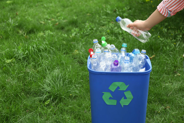 Woman throwing used bottle into trash bin outdoors, closeup. Plastic recycling - Фото, зображення