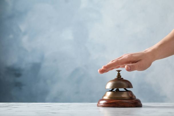 Man ringing hotel service bell at table on blue background, closeup. Space for text - Foto, imagen
