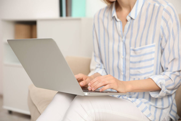 Young woman with laptop sitting indoors, closeup - 写真・画像