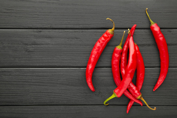 Red Hot chili peppers on black wooden background, closeup. Top view - Zdjęcie, obraz