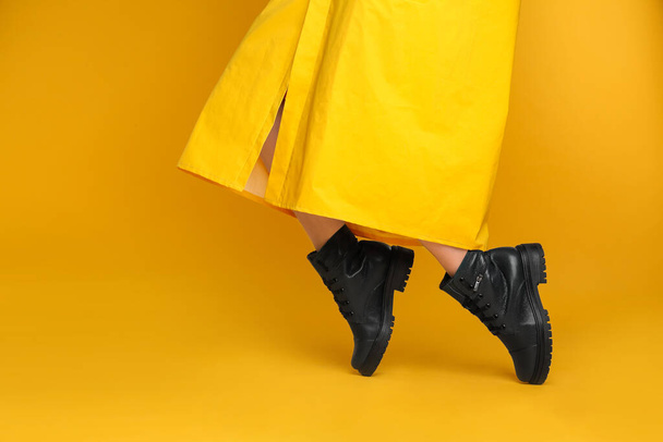 Woman wearing stylish boots on yellow background, closeup - 写真・画像