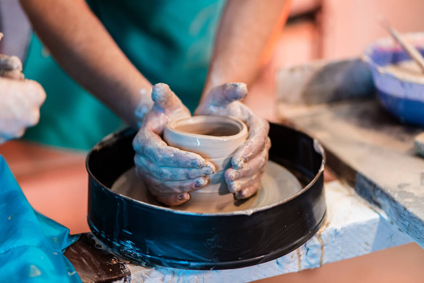 Creating a clay jar or vase. Workshop on modeling clay on pottery wheels in a pottery workshop. The sculptor in the workshop makes a jug out of earthenware closeup. - Photo, Image