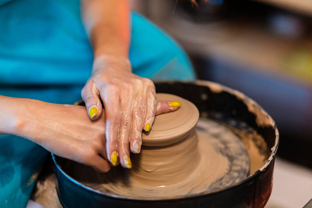 陶芸家の女性の手は陶器のホイール粘土鍋になります,閉じます.ポッターのホイール。陶器の概念. - 写真・画像