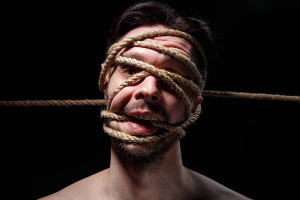 Binded brunette man with rope on face - Foto, Bild