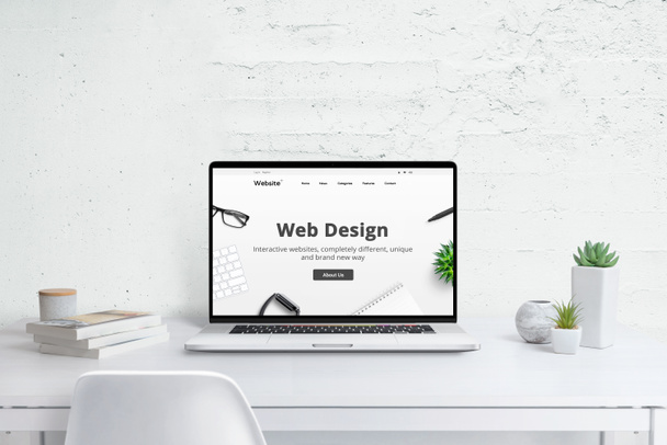 Web design studio luova konsepti. Moderni kannettava tietokone yrityksen verkkosivuilla, litteä muotoilu teema käsite. Valkoinen puinen pöytä kasveja ja kirjoja - Valokuva, kuva