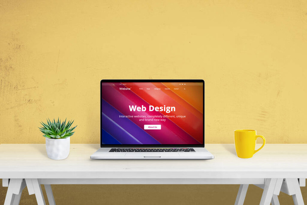 Diseño web creativo concepto de sitio web. Ordenador portátil en el escritorio con planta y taza de café al lado - Foto, imagen