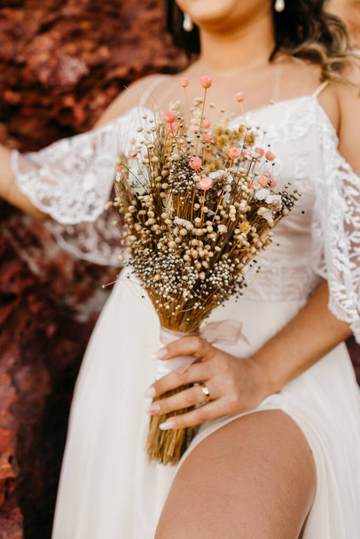 The beautiful bride wearing a white dress and holding a bouquet of flowers - Foto, Bild