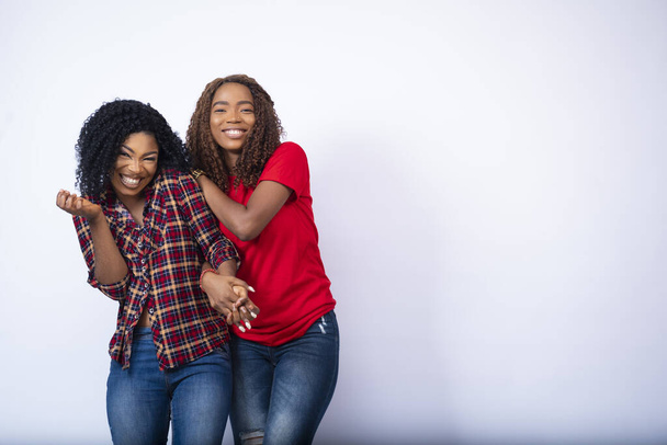 Two pretty young black female friends holding each other and laughing - Fotografie, Obrázek