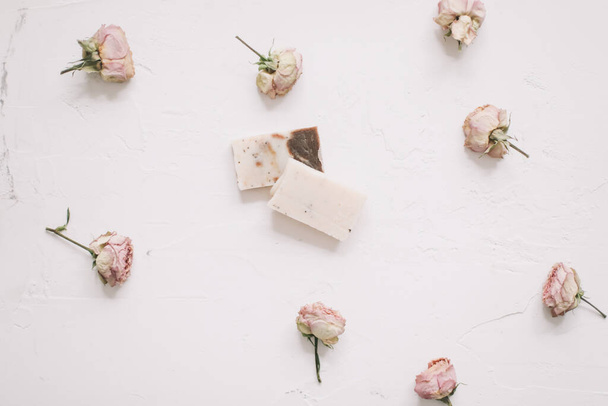 Soap bars with dry roses on white background. Handmade floral soap with rose buds. Natural cosmetics. flat lay, top view - Фото, зображення